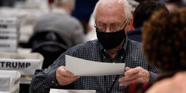 Cobb County election officials handle ballots during an audit, Monday, Nov. 16, 2020, in Marietta, Ga. (AP Photo/Mike Stewart)