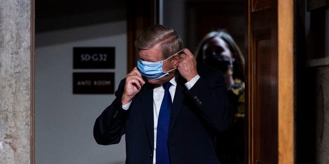 Sen. Lindsey Graham, R-S.C., puts on his face mask as he arrives for a Senate Judiciary Committee hearing on Facebook and Twitter's actions around the closely contested election on Tuesday, Nov. 17, 2020, in Washington.. (Bill Clark/Pool via AP)