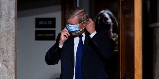 Sen. Lindsey Graham, R-S.C., puts on his face mask as he arrives for a Senate Judiciary Committee hearing on Facebook and Twitter's actions around the closely contested election on Tuesday, Nov. 17, 2020, in Washington.. (Bill Clark/Pool via AP)