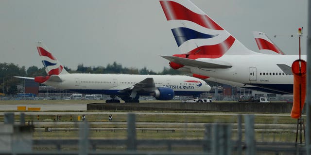 FILE: A British Airways plane, at left, is towed past other planes sitting parked at Heathrow Airport in London.