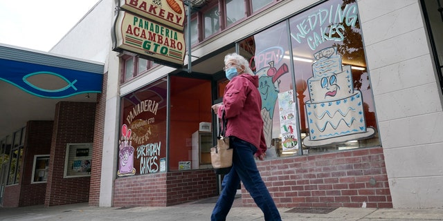 A woman wearing a face mask walks down Plumas Street in the Sutter County community of Yuba City, Calif., Tuesday, Nov. 17, 2020. (AP Photo/Rich Pedroncelli)