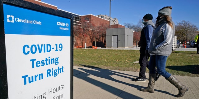 Two people walk past a sign for COVID-19 testing at the Cleveland Clinic, Wednesday, Nov. 18, 2020, in Cleveland, Ohio. (AP Photo/Tony Dejak)