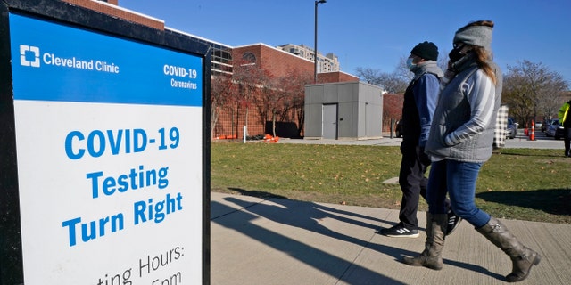 Two people walk past a sign for COVID-19 testing at the Cleveland Clinic, Wednesday, Nov. 18, 2020, in Cleveland, Ohio. (AP Photo/Tony Dejak)