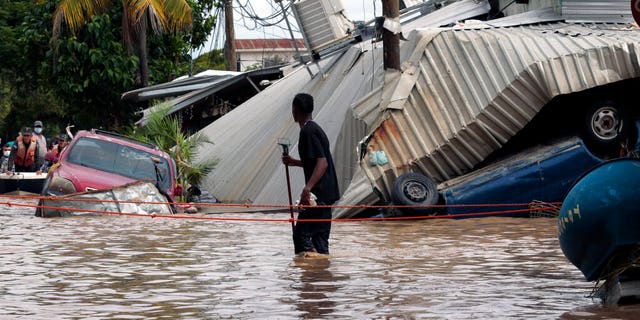 文件: A resident walking through a flooded street looks back at storm damage caused by Hurricane Eta in Planeta, 洪都拉斯.