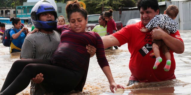 A pregnant woman is carried out of an area flooded by water brought by Hurricane Eta in Planeta, 洪都拉斯.