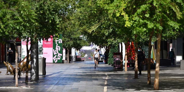 A lone man walks in a nearly empty pedestrian mall in Adelaide, Australia, Thursday, Nov. 19, 2020. South Australia state, which includes the city of Adelaide, is in a six-day lockdown as schools, universities, bars and cafes closed from Thursday and only one person from each household will be allowed to leave home each day, and only for specific reasons. (David Mariuz/AAP Image via AP)