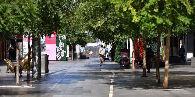 A lone man walks in a nearly empty pedestrian mall in Adelaide, Australia, Thursday, Nov. 19, 2020. South Australia state, which includes the city of Adelaide, is in a six-day lockdown as schools, universities, bars and cafes closed from Thursday and only one person from each household will be allowed to leave home each day, and only for specific reasons. (David Mariuz/AAP Image via AP)