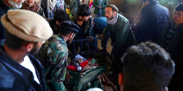 Relatives stand around the dead body of a boy who was killed by a mortar shell attack in Kabul, 阿富汗, 星期六, 十一月. 21, 2020. Mortar shells slammed into different parts of the Afghan capital on Saturday. (AP Photo/Rahmat Gul)