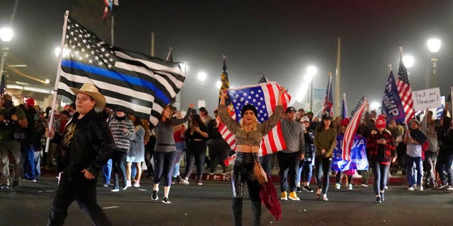 Demonstrators march across Pacific Coast Highway Saturday, Nov. 21, 2020 during a protest against a stay-at-home order amid the COVID-19 pandemic in Huntington Beach, Calif.