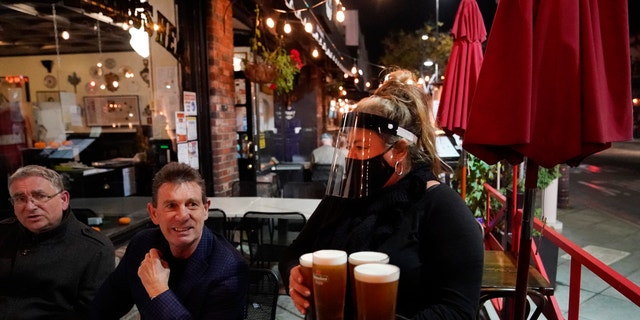 A waitress serves beer to patrons at Ye Olde King's Head in Santa Monica, California.  Los Angeles County this month announced new coronavirus restrictions banning in-person meals for at least three weeks as cases increase.  (AP Photo / Marcio Jose Sanchez)