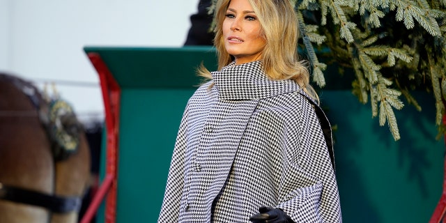 First lady Melania Trump stands next to the 2020 Official White House Christmas tree as it is presented on the North Portico of the White House, Monday, Nov. 23, 2020, in Washington. (AP Photo/Andrew Harnik)