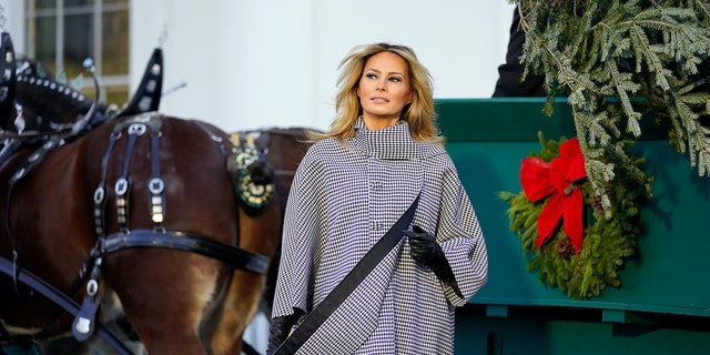 First lady Melania Trump stands next to the official 2020 White House Christmas tree as it is presented on the North Portico of the White House on Nov. 23, 2020, in Washington. 