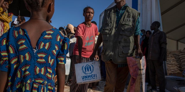 Tigray refugees who fled the conflict in Ethiopia's Tigray region, receive aid from the UNHCR at Umm Rakouba refugee camp in Qadarif, eastern Sudan, Tuesday, Nov. 24, 2020. (AP Photo/Nariman El-Mofty)