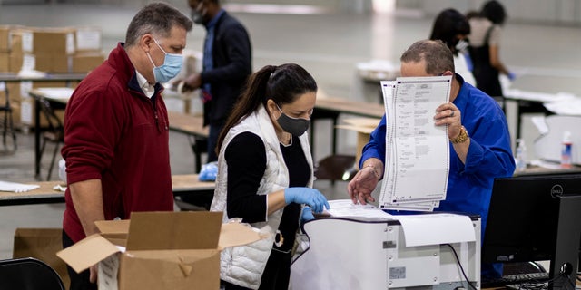 Workers scan ballots as the Fulton County presidential recount gets underway Wednesday, Nov. 25, 2020, at the Georgia World Congress Center in Atlanta. (Associated Press)