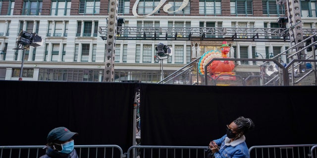 Pedestrians walk past black curtains along 34th Street believed to block the view of a pre-tap of Macy's Thanksgiving parade outside the New York flagship store on Wednesday, November 25, 2020 (AP Photo / Mary Altaffer)