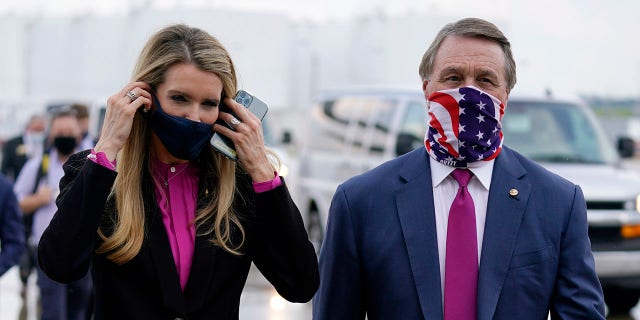 In this July 15, 2020, file photo Sen. 凯莉·洛夫勒(Kelly Loeffler), R-Ga., puts on a face mask as she walks with Sen. 大卫·珀杜R-Ga。vid Perdue), R-Ga., 对, at UPS Hapeville Airport Hub in Atlanta. Both Perdue and Loeffler have said they support $ 2,000 刺激检查. (美联社照片/ Evan Vucci, 文件)