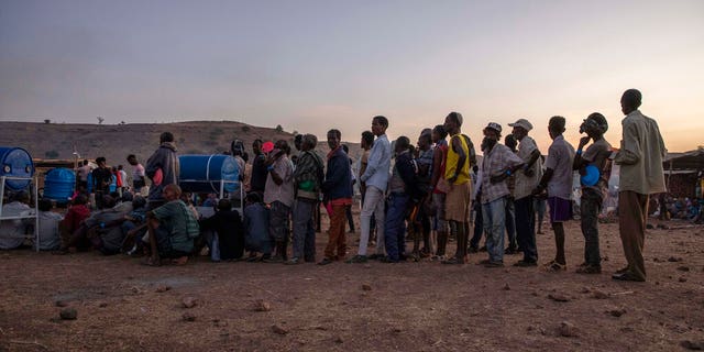 Tigray men who fled the conflict in Ethiopia's Tigray region, stand in line to receive food cooked by Sudanese women volunteers, at Umm Rakouba refugee camp in Qadarif, eastern Sudan, Thursday, Nov. 26, 2020. (AP Photo/Nariman El-Mofty)