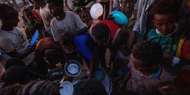 Tigray men who fled the conflict in Ethiopia's Tigray region, receive cooked rice from charity organization Muslim Aid, at Umm Rakouba refugee camp in Qadarif, eastern Sudan, Friday, Nov. 27, 2020. Ethiopian Prime Minister Abiy Ahmed again ruled out dialogue with the leaders of the defiant Tigray region Friday but said he was willing to speak to representatives 