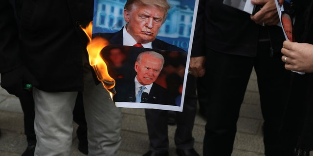 A group of protesters burn pictures of the U.S. President Donald Trump, top, and the President-elect Joe Biden in a gathering in front of Iranian Foreign Ministry on Saturday, Nov. 28, 2020, a day after the killing of Mohsen Fakhrizadeh an Iranian scientist linked to the country's nuclear program by unknown assailants near Tehran. (AP Photo/Vahid Salemi)