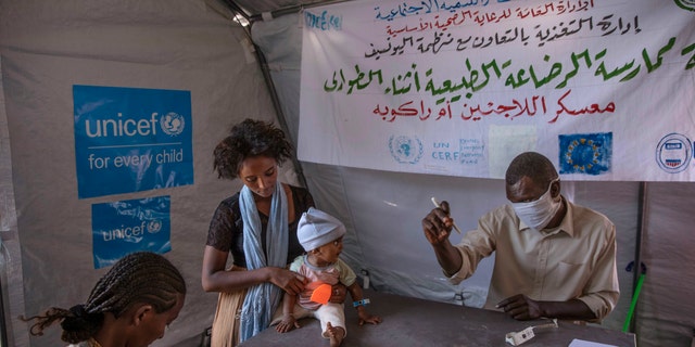 Tigray women who fled the conflict in Ethiopia's Tigray region, take shelter inside a UNICEF tent, as Filippo Grandi, U.N. High Commissioner for Refugees, visits Umm Rakouba refugee camp in Qadarif, eastern Sudan, Saturday, Nov. 28, 2020. (AP Photo/Nariman El-Mofty)