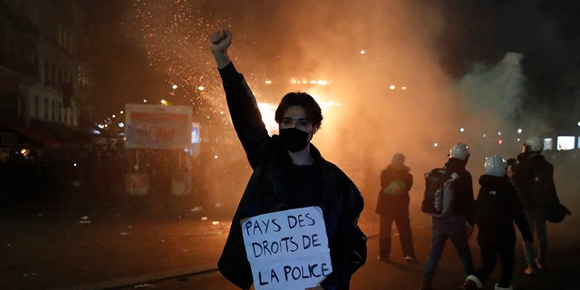 A protester holds a poster reading "Land of rights for the police" during a demonstration against a security law Saturday, Nov. 28, 2020 in Paris. Thousands of critics of a proposed security law that would restrict sharing images of police officers in France gathered across the country in protest, and officers in Paris who were advised to behave responsibly during the demonstrations fired tear gas to disperse rowdy protesters in the largely peaceful crowd. The cause has gained fresh impetus in recent days after footage emerged of French police officers beating up a Black man, triggering a nationwide outcry. (AP Photo/Francois Mori)
