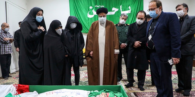 Iranian justice chief Ayatollah Ebrahim Raisi pays tribute to the body of murdered scientist Mohsen Fakhrizadeh among his family in Tehran, Iran on Saturday, November 28, 2020. Iranian officials have accused Israel of the murder of Fakhrizadeh, who directed Tehran's dissolved military nuclear power.  program.  (Mizan News Agency via AP)