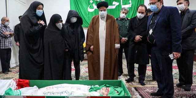 Iranian justice chief Ayatollah Ebrahim Raisi pays tribute to the body of murdered scientist Mohsen Fakhrizadeh among his family in Tehran, Iran on Saturday, November 28, 2020. Iranian officials have accused Israel of the murder of Fakhrizadeh, who directed Tehran's dissolved military nuclear power.  program.  (Mizan News Agency via AP)