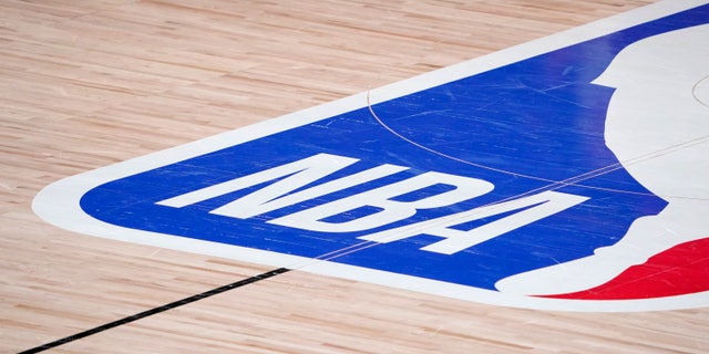 In this Sept. 2, 2020, file photo, the NBA logo is displayed at center court during a first-round playoff game between the Houston Rockets and Oklahoma City Thunder in Lake Buena Vista, Fla.