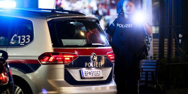 A police officer with a flashlight stays in position at the scene after gunshots were heard in Vienna. (Photo/Ronald Zak)