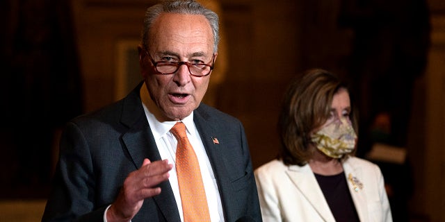 In this Aug. 6, 2020, file photo Senate Minority Leader Sen. Chuck Schumer of New York speaks to reporters as House Speaker Nancy Pelosi of California listens at right on Capitol Hill in Washington. (AP Photo/Carolyn Kaster, File)