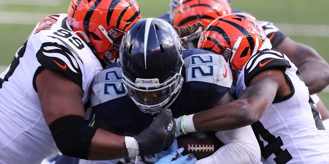 Tennessee Titans' Derrick Henry (22) is tackled by Cincinnati Bengals' Christian Covington (99) and Vonn Bell (24) during the first half of an NFL football game, Sunday, Nov. 1, 2020, in Cincinnati. (AP Photo/Jay LaPrete)