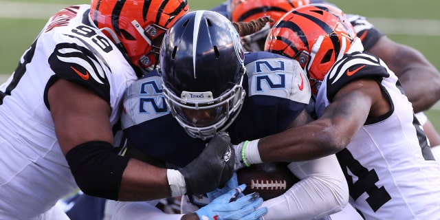Tennessee Titans' Derrick Henry (22) is tackled by Cincinnati Bengals' Christian Covington (99) and Vonn Bell (24) during the first half of an NFL football game, Sunday, Nov. 1, 2020, in Cincinnati. (AP Photo/Jay LaPrete)