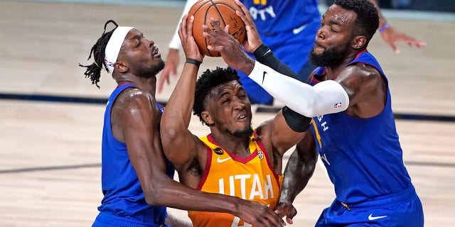 In this Aug. 30, 2020, file photo, Utah Jazz's Donovan Mitchell, center, goes up to shoot as the Denver Nuggets' Jerami Grant, left, and Paul Millsap, right, defend during the second half of an NBA basketball first-round playoff game in Lake Buena Vista, Fla. Mitchell agreed Nov. 22, 2020, to a five-year, $163 million extension to remain with the Jazz. (AP Photo/Ashley Landis, File)