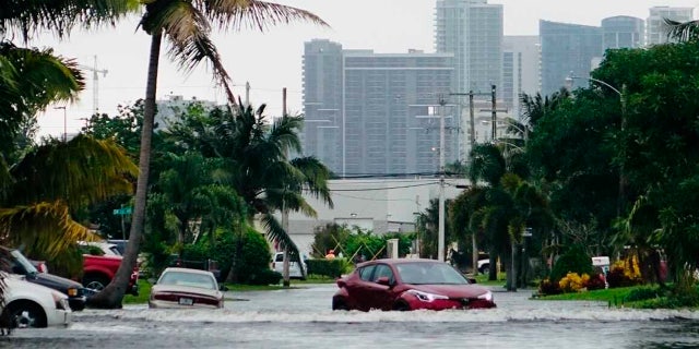 A car navigates a flooded street in the Melrose Manors neighborhood west of downtown Fort Lauderdale on Monday, Nov.9, 2020.
