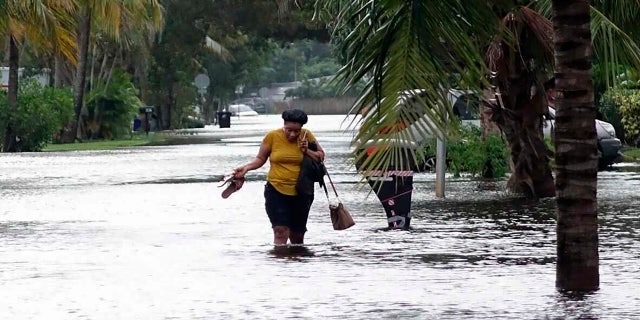 A woman crosses through floodwaters in the Melrose Place neighborhood in Fort Lauderdale, Fla., on Monday, Nov. 9, 2020.