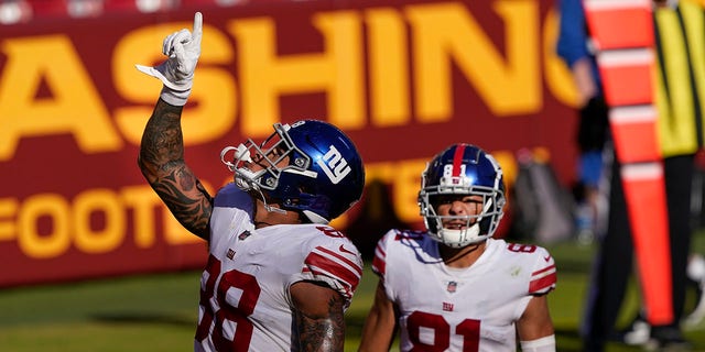 New York Giants tight end Evan Engram (88) pointing upwards after scoring a touchdown against the Washington Football Team, Sunday, Nov. 8, 2020, in Landover, Md. Also on the field is teammate wide receiver Austin Mack (81). (AP Photo/Susan Walsh)