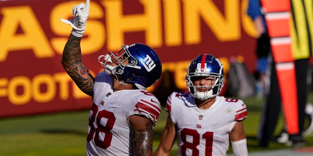New York Giants tight end Evan Engram (88) pointing upwards after scoring a touchdown against the Washington Football Team, Sunday, Nov. 8, 2020, in Landover, Md. Also on the field is teammate wide receiver Austin Mack (81). (AP Photo/Susan Walsh)