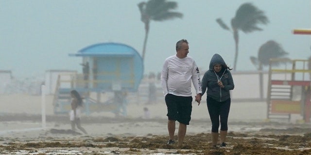 A couple walks along the beach during a downpour, Sunday, Nov. 8, 2020, on Miami Beach, Florida's famed South Beach.