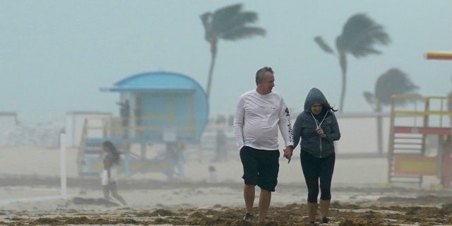 A couple walks along the beach during a downpour, Sunday, Nov. 8, 2020, on Miami Beach, Florida's famed South Beach.