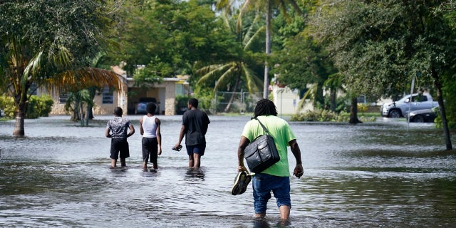 Residents walk a flooded street to reach their homes, Monday, Nov. 9, 2020 in Fort Lauderdale, Fla.