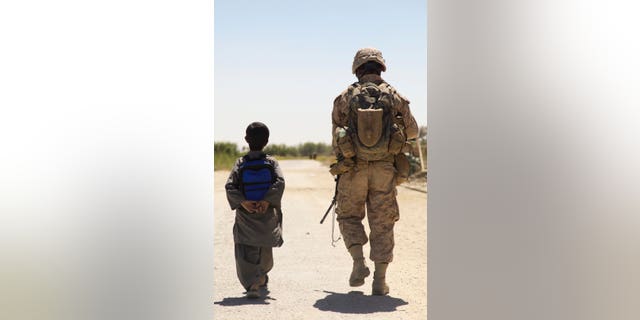 US Marines patrol the Nawa Bazaar with an Afghan boy in the Nawa District, Helmand province (US Marine Corps photo by Cpl Jeremy Harris / released)