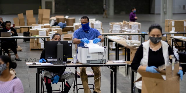 Workers scan ballots as the Fulton County presidential recount gets under way Wednesday morning, Nov. 25, 2020 at the Georgia World Congress Center in Atlanta. County election workers across Georgia have begun an official machine recount of the roughly 5 million votes cast in the presidential race in the state. The recount was requested by President Donald Trump after certified results showed him losing the state to Democrat Joe Biden by 12,670 votes, or 0.25%. (AP Photo/Ben Gray)