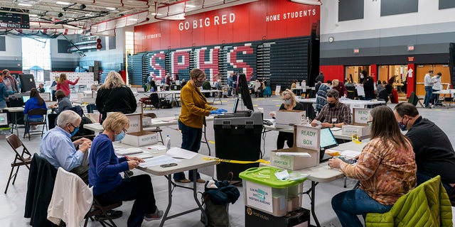 On November 3, 2020, polling station Rebecca Brandt, center, runs a voting machine with absent ballots in the gym at Sun Prairie High School in Sun Prairie, Wisconsin.  (Photo by Andy Manis / Getty Images)