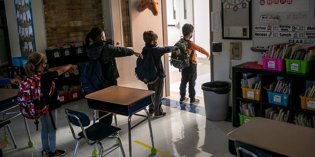 A kindergarten class socially distances while preparing to leave their classroom at Stark Elementary School on Oct. 21, 2020 in Stamford, Conn. Stamford Public Schools is continuing the fall semester with a hybrid model of in-class and distance learning, occasionally quarantining individual classes when a student or faculty member tests positive for COVID-19. (John Moore/Getty Images)