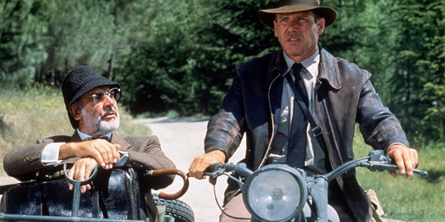 American actor Harrison Ford as the eponymous archaeologist and Scottish actor Sean Connery as his father, Henry Jones, during the motorcycle chase scene from the film "Indiana Jones and the Last Crusade" in 1989