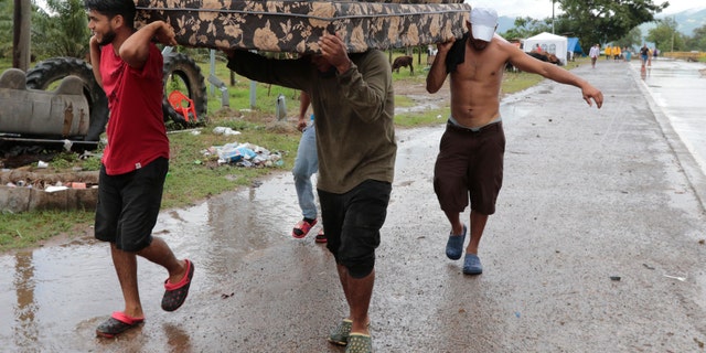 Neighbors help each other as they evacuate the area before Hurricane Iota makes landfall in San Manuel Cortes, Honduras, Monday, November 16, 2020.