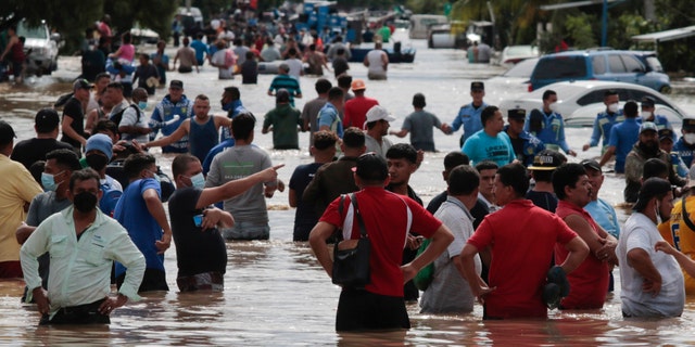 Residents wade through a flooded road in the aftermath of Hurricane Eta in Planeta, Honduras, on Nov. 5, 2020.