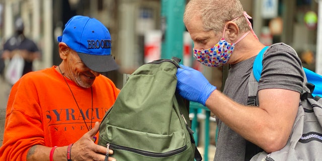 Jeffrey Newman (right) is giving someone a backpack filled with necessities. (Courtesy of Backpacks for the Street)