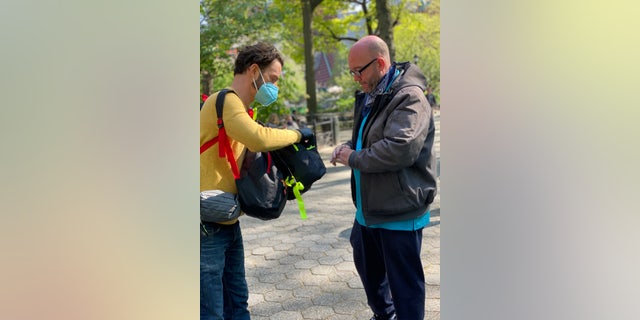 Jayson Conner hands someone a backpack. Conner himself experienced homelessness in the early 2000s. (Courtesy of Backpacks for the Street)