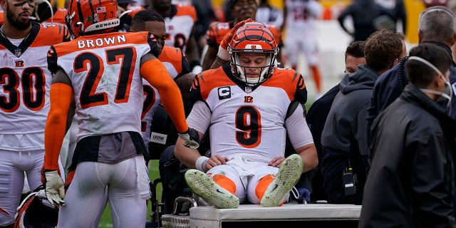 Cincinnati Bengals quarterback Joe Burrow (9) is consoled by teammates as he is carted off the field during the second half of an NFL football game against the Washington Football Team, Sunday, Nov. 22, 2020, in Landover. Burrow was carted off the field with a left knee injury. (AP Photo/Susan Walsh)